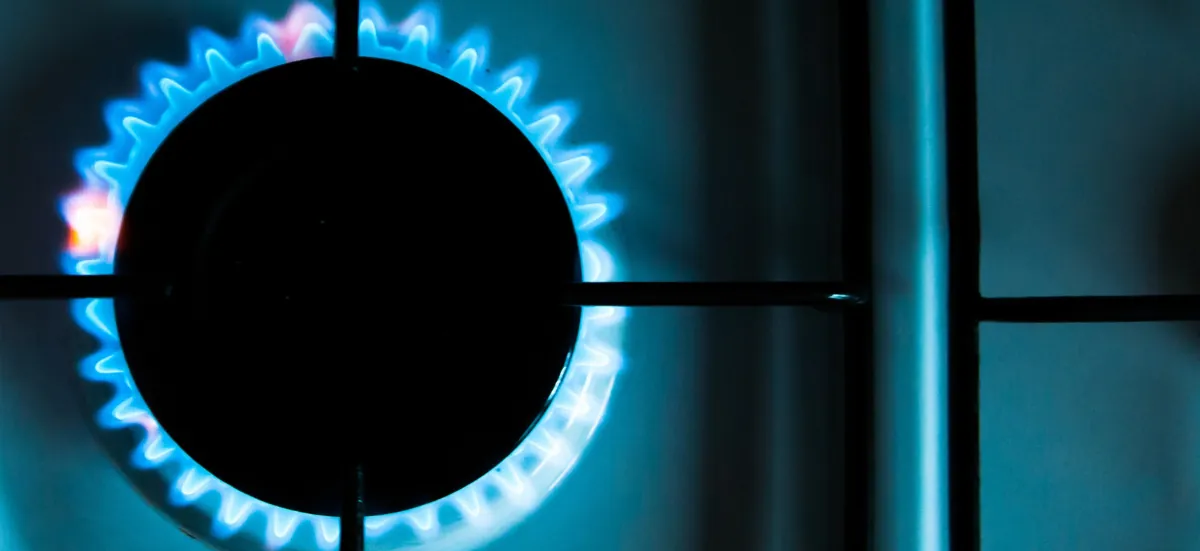 Brûleur de gaz allumé sur une plaque de cuisson, flamme bleue vue de dessus